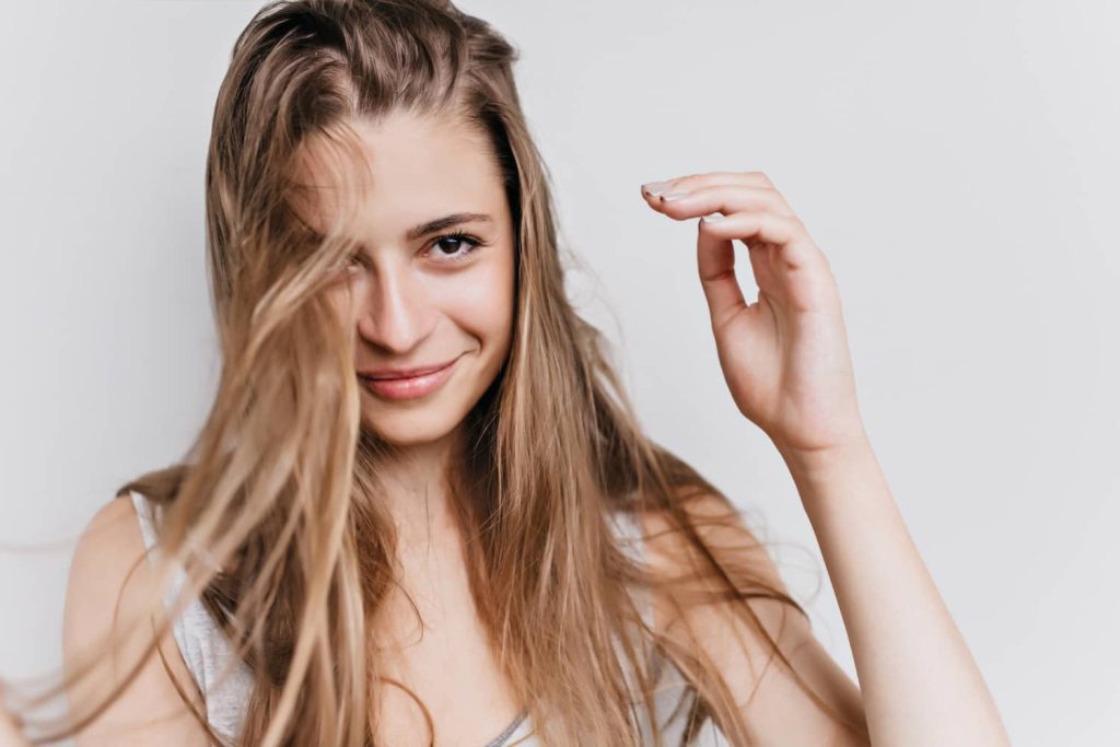 Mulher com cabelo saudável a representar vitaminas para queda de cabelo feminino