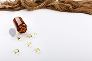 Vitaminas para queda de cabelo em cápsulas ao lado de cabelo saudável